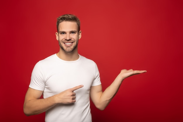 Sorrindo jovem apontando com a mão e o dedo isolado no vermelho