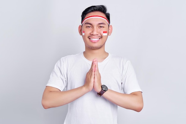 Sorrindo jovem asiático cumprimentando para comemorar o dia da independência da indonésia em 17 de agosto isolado em fundo branco