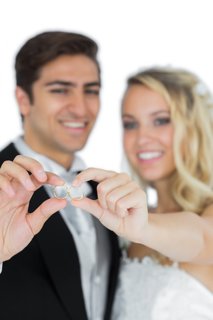 Sorrindo jovem casado segurando seus anéis de casamento