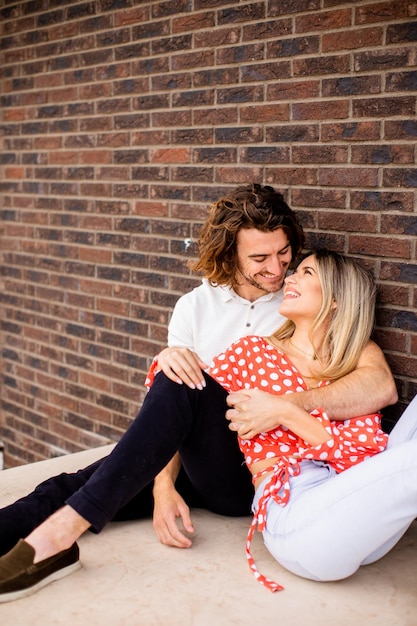 Sorrindo jovem casal apaixonado na frente da parede de tijolos da casa