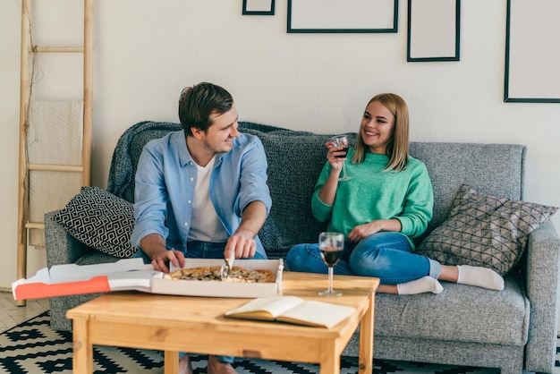 Sorrindo jovem casal comemorando com comida e vinho