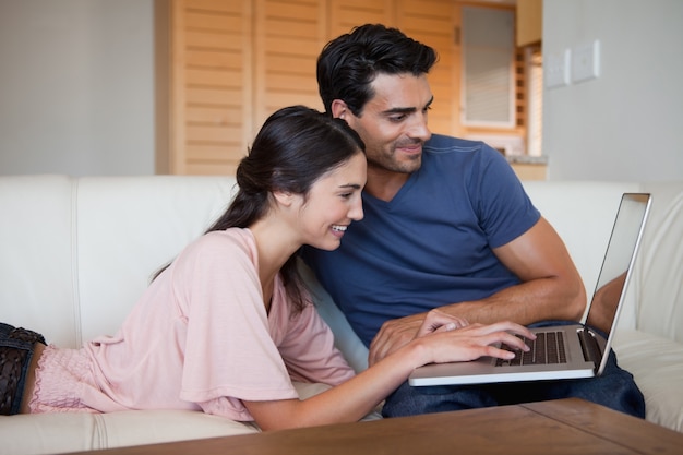 Sorrindo jovem casal usando um laptop
