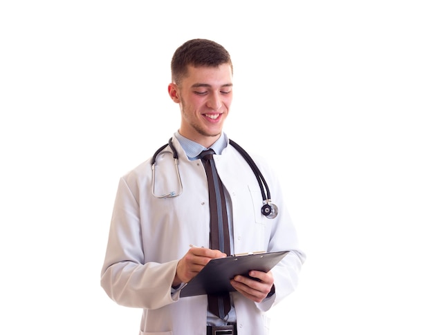 Sorrindo jovem com cabelo castanho em gravata de camisa azul e vestido de médico branco com estetoscópio