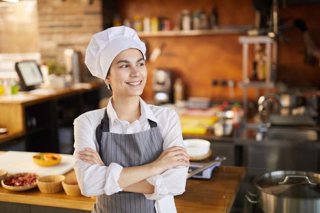 Sorrindo jovem cozinheiro usando chapéu de chefs