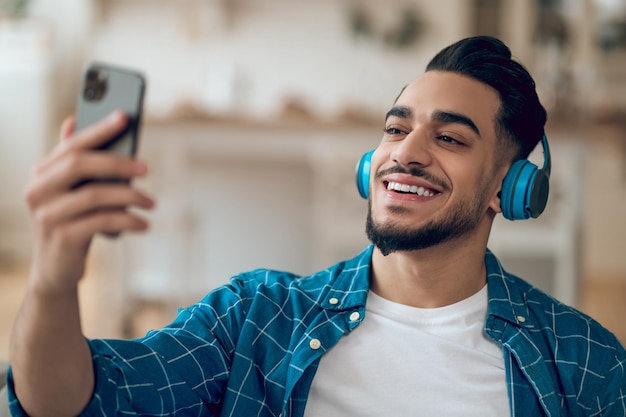 Sorrindo jovem em uma camiseta azul e com fones de ouvido