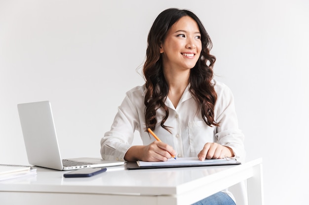 Sorrindo jovem empresária asiática tomando notas