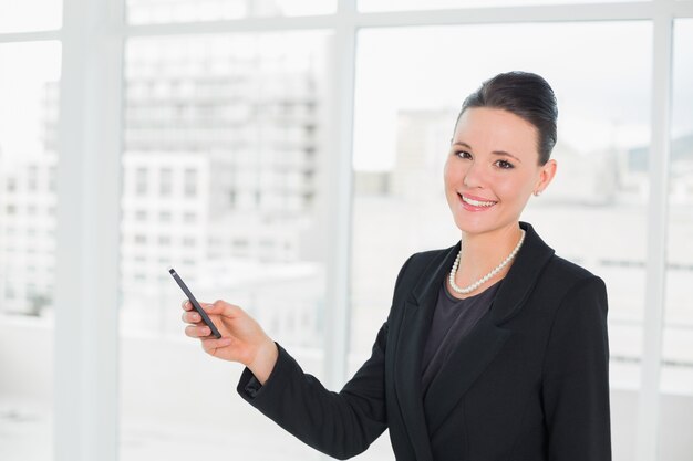 Sorrindo jovem empresária elegante olhando para celular