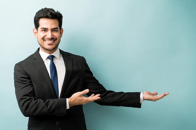 Sorrindo jovem executivo masculino mostrando o espaço vazio contra o fundo colorido