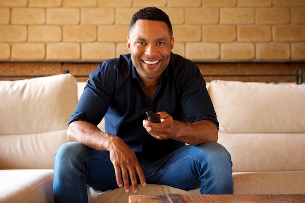 Sorrindo, jovem, homem americano africano, sentar sofá, e, observar tv