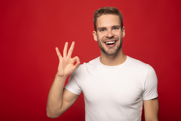 sorrindo jovem mostrando sinal bem isolado no vermelho