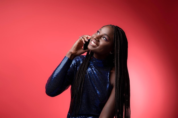 Sorrindo jovem negra em vestido de lantejoulas falando no celular