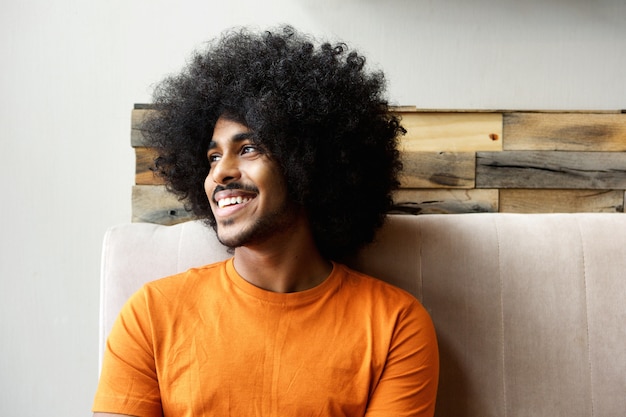 Foto sorrindo jovem negro com afro a desviar o olhar