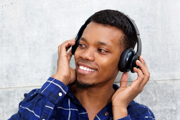 Sorrindo jovem negro com fones de ouvido, ouvindo música