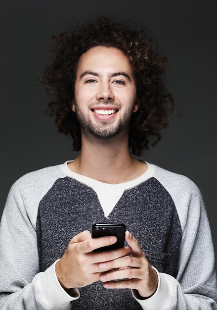 Sorrindo jovem segurando smartphone e olhando para ele