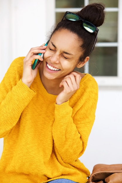 Foto sorrindo jovem sentado do lado de fora e falando no celular