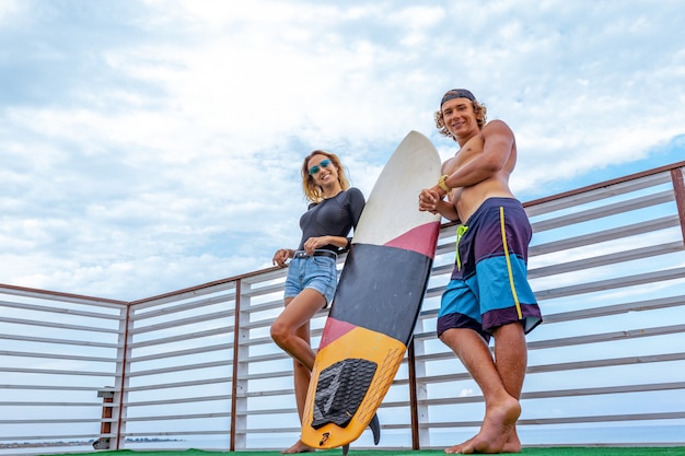 Sorrindo jovens surfistas ativos casal relaxando na praia após esporte com prancha de surf. Estilo de vida saudável. Esportes Aquáticos Extremos
