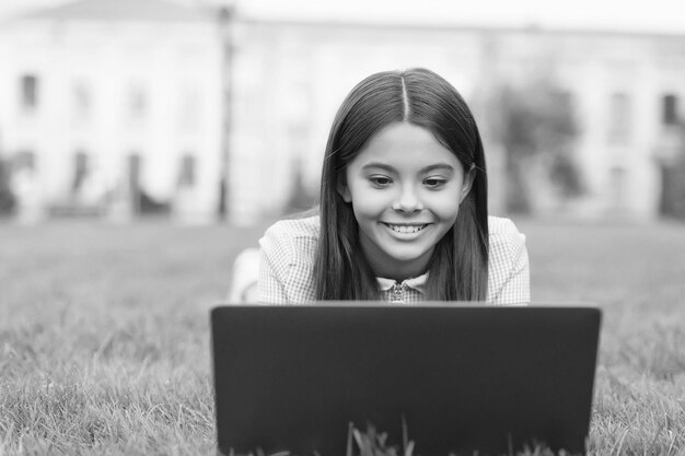 Sorrindo linda adolescente tendo bate-papo on-line ou videochamada com um amigo na comunicação da escola de laptop