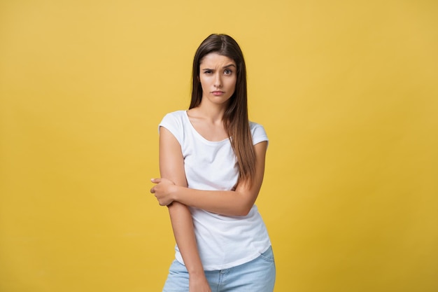 Sorrindo linda jovem de camisa branca olhando para a câmera estúdio de três quartos filmado em fundo amarelo