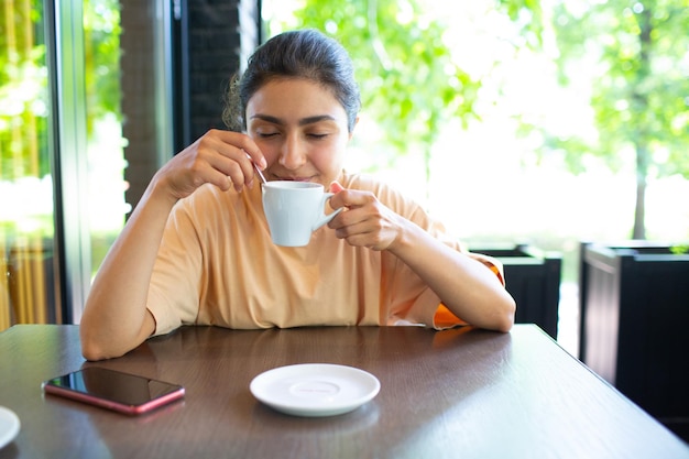 Sorrindo linda jovem tomando café lá fora