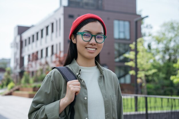 sorrindo linda turista asiática segurando mochila olhando para a câmera no conceito de viagens de rua