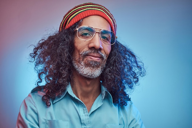 Sorrindo macho rastafari africano vestindo uma camisa azul e gorro. Retrato de estúdio em um fundo azul.