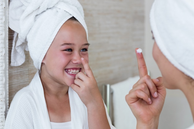 Foto sorrindo, mãe e filha, aplicar creme hidratante no nariz