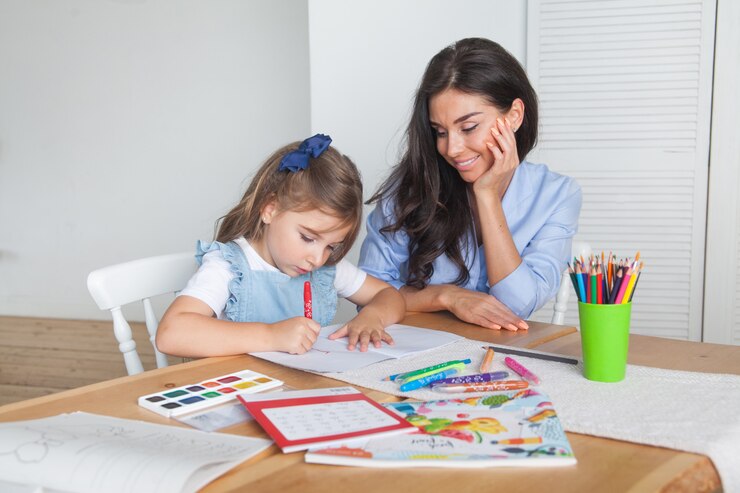 Sorrindo, mãe e filha se preparando para as aulas e desenha à mesa com lápis e tintas