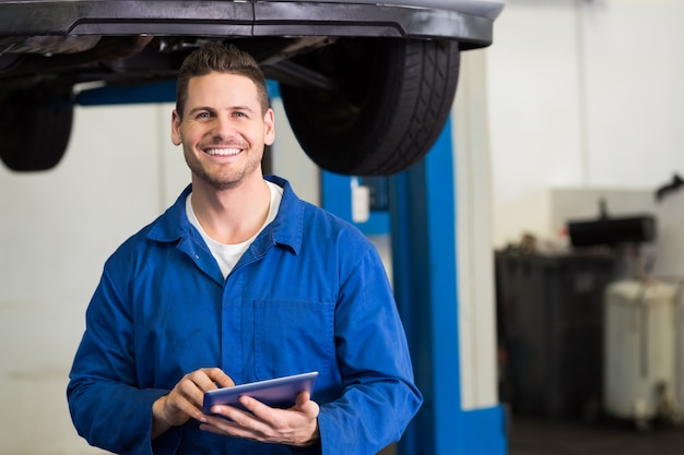 Sorrindo, mecânico, olhando câmera, usando, tabuleta, em, a, reparar, garagem