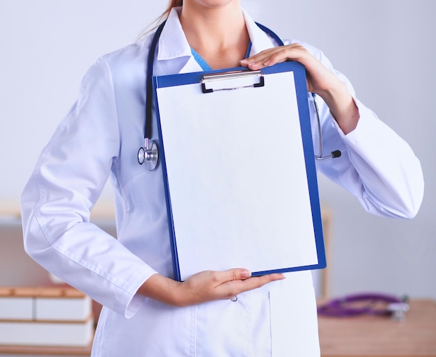 Sorrindo médica com uma pasta em uniforme permanente no hospital