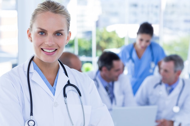 Sorrindo, médico feminino, olhando câmera, enquanto, dela, colegas, trabalhos