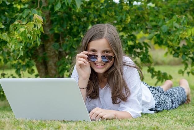 Sorrindo, menina adolescente, mentir grama, usando computador portátil