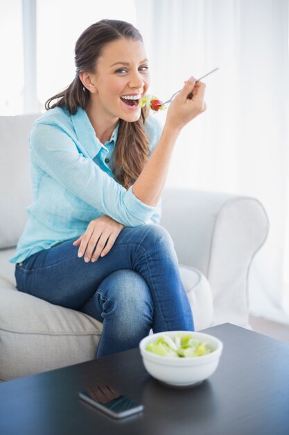 Sorrindo mulher atraente comendo salada saudável