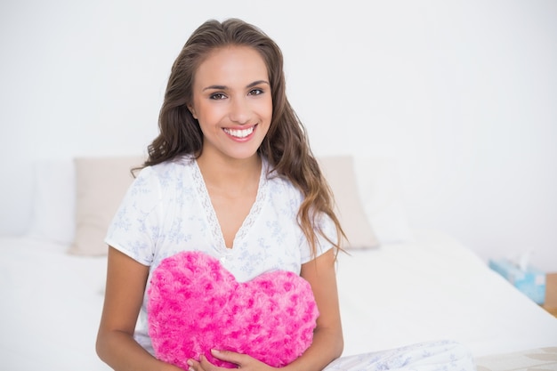 Sorrindo mulher atraente segurando travesseiro de coração