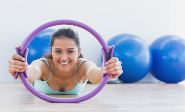 Sorrindo, mulher desportiva, com anel de exercício no estúdio de ginástica