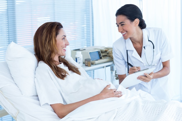 Sorrindo, mulher grávida com seu médico