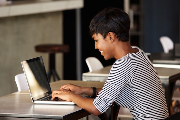 Sorrindo, mulher jovem, usando computador portátil, em, café