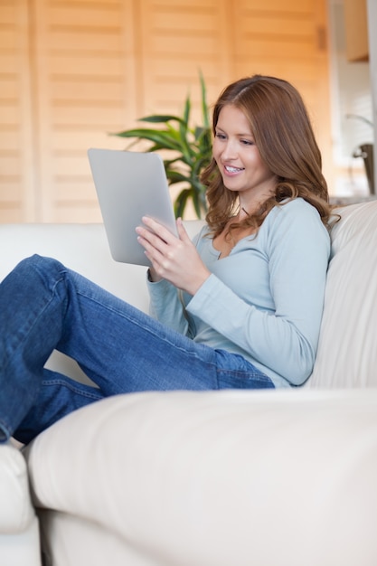 Sorrindo mulher no sofá com o seu tablet