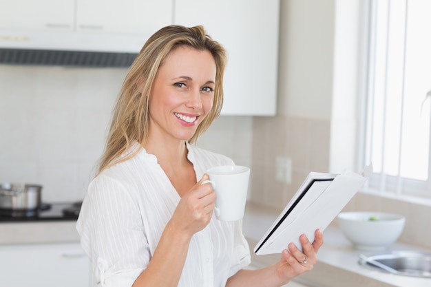 Sorrindo mulher segurando caneca e jornal