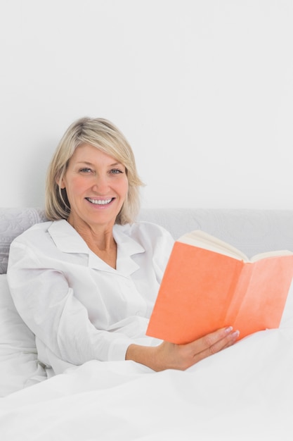 Sorrindo, mulher, sentada, cama, leitura