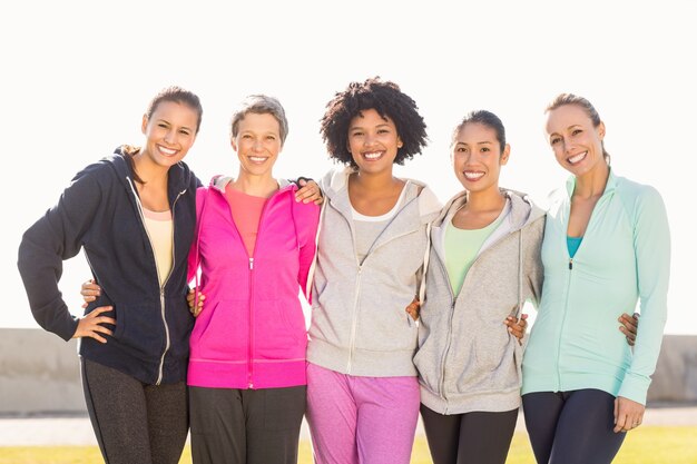 Sorrindo mulheres desportivas com os braços uns aos outros