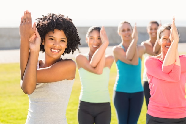 Sorrindo mulheres desportivas fazendo pose de águia na aula de ioga