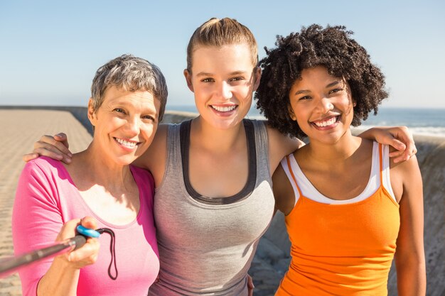 Sorrindo mulheres desportivas tomando selfies com selfiestick