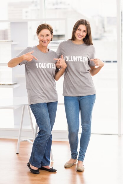 Sorrindo mulheres voluntárias mostrando suas camisas