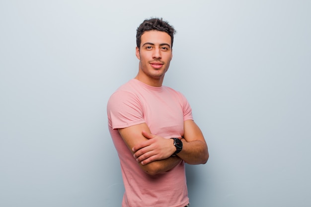 sorrindo na frente com os braços cruzados e uma expressão feliz, confiante e satisfeita, vista lateral