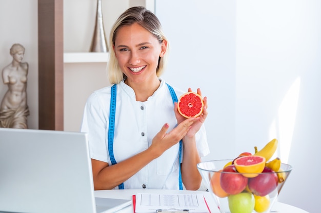 Sorrindo nutricionista no escritório segurando uma fruta