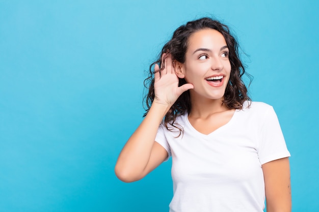 sorrindo, olhando curiosamente para o lado, tentando ouvir fofocas ou ouvir um segredo