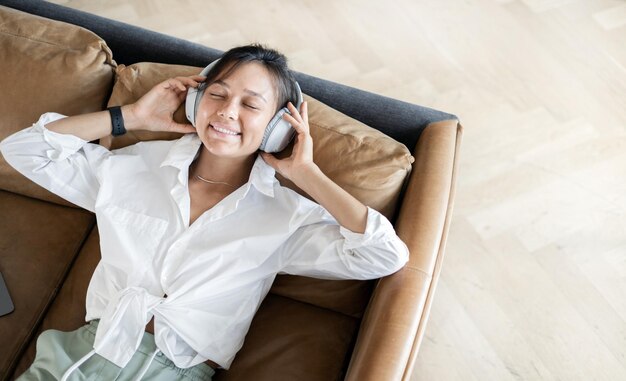 Sorrindo ouvindo um audiolivro com fones de ouvido usando um aplicativo com livros Uma mulher