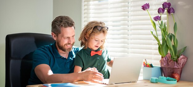 Sorrindo, pai e filho de óculos usam laptop em casa blog da família menino nerd faz lição de casa com professor webinar videoaula educação on-line no laptop homeschooling e e-learning de volta às aulas