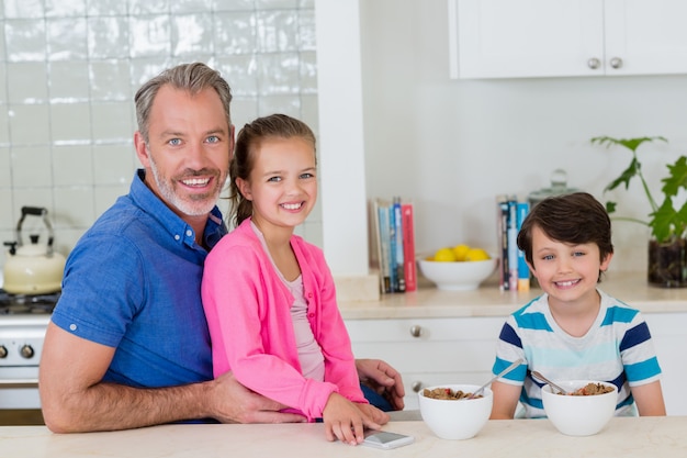 Sorrindo, pai e filhos tomando café na cozinha