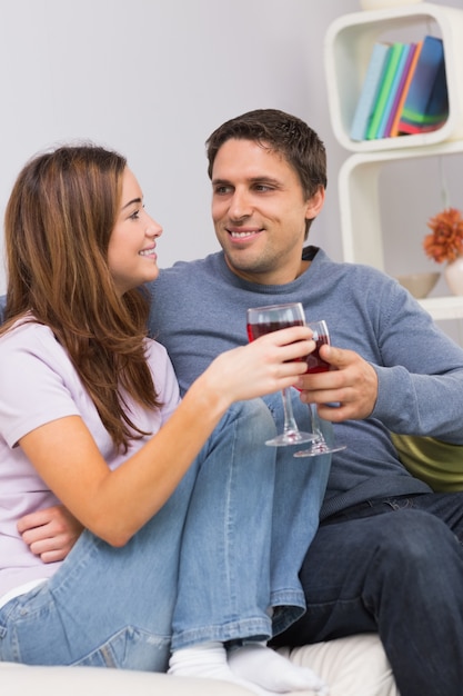 Sorrindo, par jovem, brindar, copos de vinho, ligado, sofá, casa